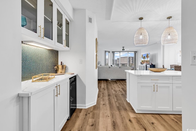 139 S Dunes Dr Unit 304, Pawleys Island, SC 29585 - kitchen featuring white cabinets, backsplash, glass insert cabinets, light wood-style flooring, and open floor plan