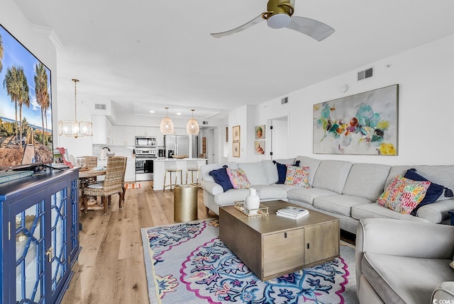 139 S Dunes Dr Unit 304, Pawleys Island, SC 29585 - living area with light wood-type flooring, ceiling fan, a chandelier, and ornamental molding