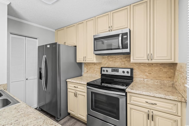 4115 Little River Rd Unit 1-E, Myrtle Beach, SC 29577 - kitchen with cream cabinetry, appliances with stainless steel finishes, light countertops, ornamental molding, and a textured ceiling