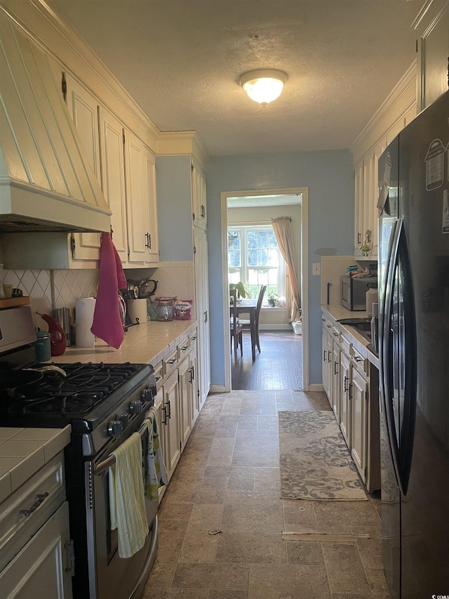 1872 Harris Short Cut Rd, Conway, SC 29526 - kitchen featuring freestanding refrigerator, stainless steel range with gas cooktop, premium range hood, tasteful backsplash, and tile countertops