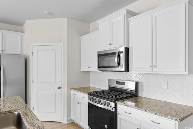 490 Calhoun Falls Dr, Myrtle Beach, SC 29579 - kitchen featuring stainless steel appliances, light stone counters, decorative backsplash, white cabinets, and light wood-type flooring