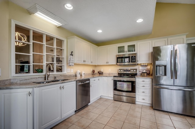 1010 Swan Lake Dr, North Myrtle Beach, SC 29582 - kitchen with stainless steel appliances, light tile patterned floors, white cabinetry, light stone counters, and glass insert cabinets