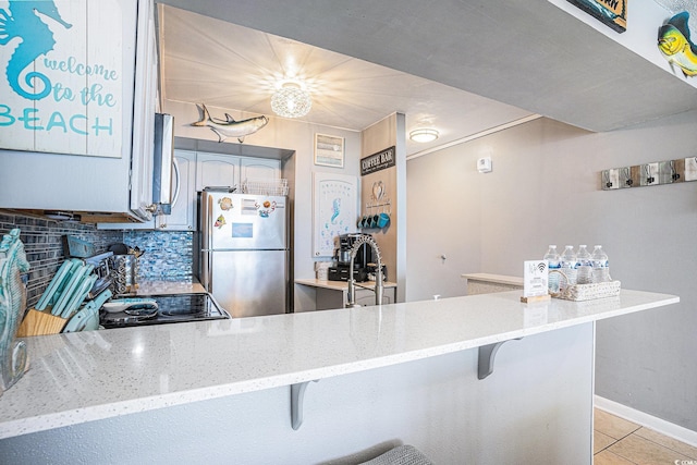 9400 Shore Dr Unit 716, Myrtle Beach, SC 29572 - kitchen featuring stainless steel appliances, light tile patterned flooring, a breakfast bar, backsplash, and light stone countertops