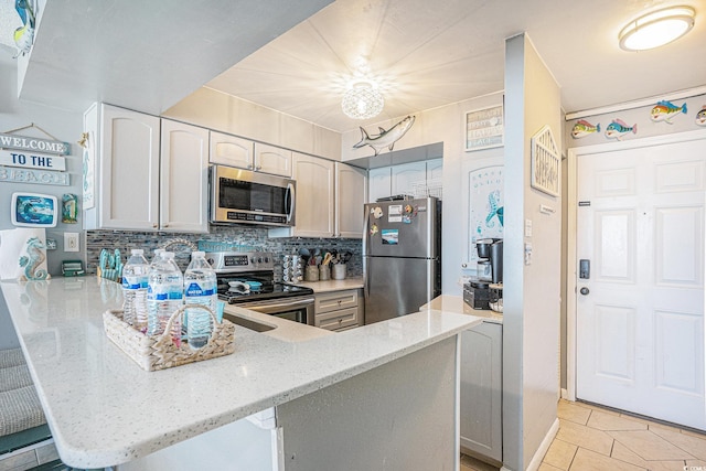 9400 Shore Dr Unit 716, Myrtle Beach, SC 29572 - kitchen featuring appliances with stainless steel finishes, a peninsula, light stone counters, decorative backsplash, and light tile patterned floors