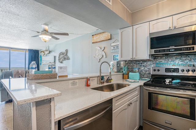 9400 Shore Dr Unit 716, Myrtle Beach, SC 29572 - kitchen with appliances with stainless steel finishes, a peninsula, backsplash, light stone counters, and a ceiling fan