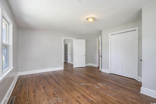 602 3rd Ave N, Myrtle Beach, SC 29577 - unfurnished bedroom featuring multiple windows, dark wood-type flooring, and a closet