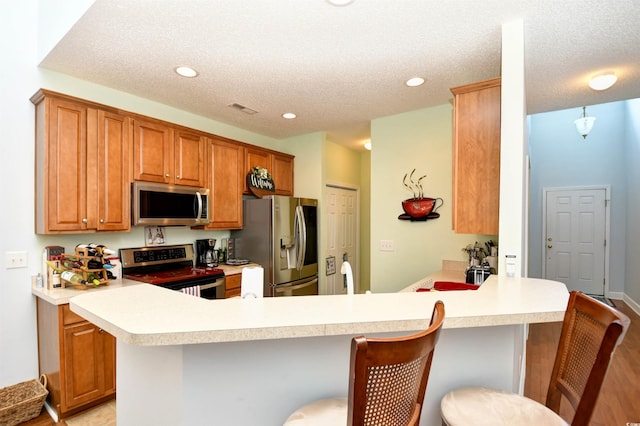 6172 Catalina Dr Unit 113, North Myrtle Beach, SC 29582 - kitchen featuring appliances with stainless steel finishes, a peninsula, light countertops, a breakfast bar, and recessed lighting