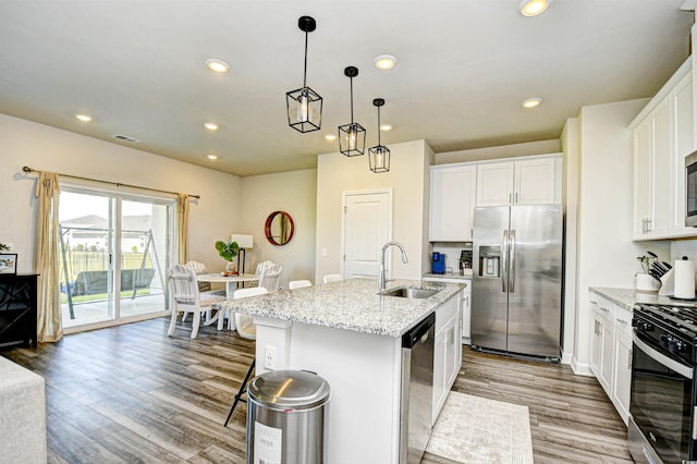 2325 Copper Creek Loop, Longs, SC 29568 - kitchen featuring stainless steel appliances, wood finished floors, recessed lighting, white cabinets, and a center island with sink