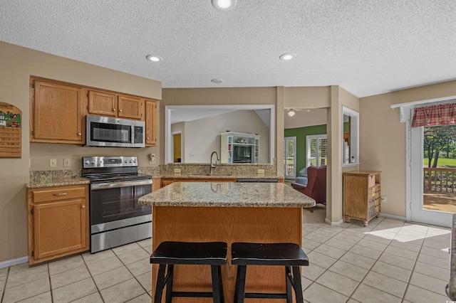 3975 River Hills Dr, Little River, SC 29566 - kitchen with stainless steel appliances, a kitchen island, light tile patterned floors, light stone countertops, and a textured ceiling