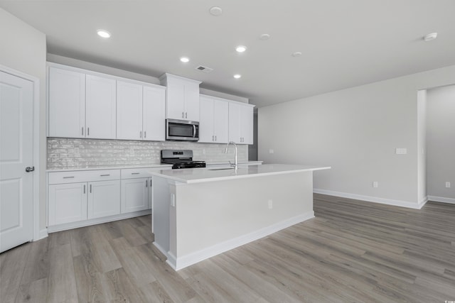 4881 Hopespring St, Myrtle Beach, SC 29579 - kitchen featuring stainless steel microwave, electric range, backsplash, an island with sink, and light wood-style flooring