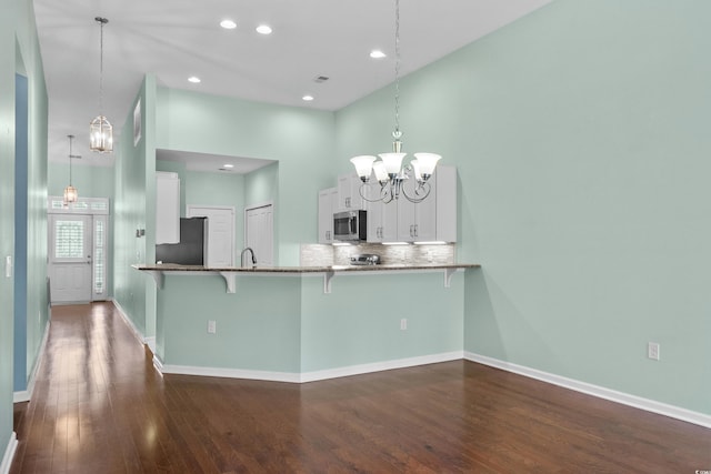 156 Parmelee Dr Unit D, Murrells Inlet, SC 29576 - kitchen with refrigerator, stainless steel microwave, a breakfast bar area, a chandelier, and dark wood-style floors