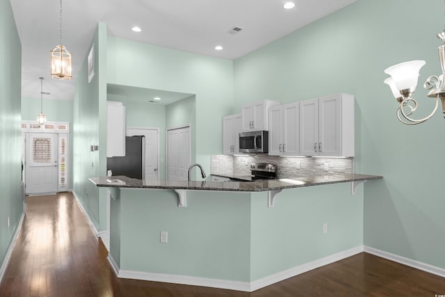 156 Parmelee Dr Unit D, Murrells Inlet, SC 29576 - kitchen with appliances with stainless steel finishes, a breakfast bar area, dark stone counters, a peninsula, and a high ceiling