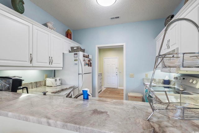 824 Castleford Cir Unit 7C, Myrtle Beach, SC 29572 - kitchen with freestanding refrigerator, light stone countertops, a textured ceiling, white cabinets, and light wood-style flooring
