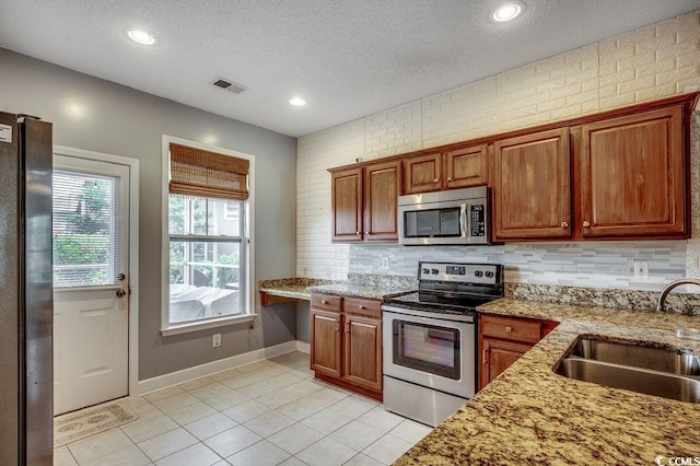 100 Culpepper Way Unit 1002, Myrtle Beach, SC 29579 - kitchen featuring appliances with stainless steel finishes, light tile patterned floors, a textured ceiling, decorative backsplash, and light stone countertops