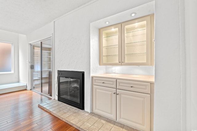 310 74th Ave N Unit 7, Myrtle Beach, SC 29572 - bar with light wood-style floors, a glass covered fireplace, a textured wall, and a textured ceiling