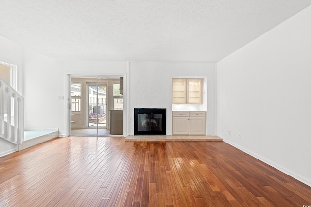 310 74th Ave N Unit 7, Myrtle Beach, SC 29572 - unfurnished living room with wood-type flooring, a glass covered fireplace, and a textured ceiling