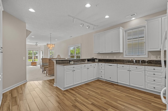 907 Tidewater Dr, North Myrtle Beach, SC 29582 - kitchen featuring white dishwasher, light wood-type flooring, white cabinets, a peninsula, and a textured ceiling
