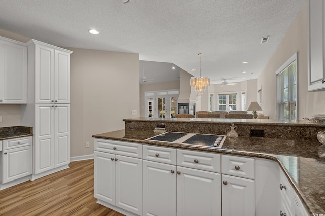 907 Tidewater Dr, North Myrtle Beach, SC 29582 - kitchen featuring black electric stovetop, light wood-style floors, white cabinets, dark stone counters, and ceiling fan