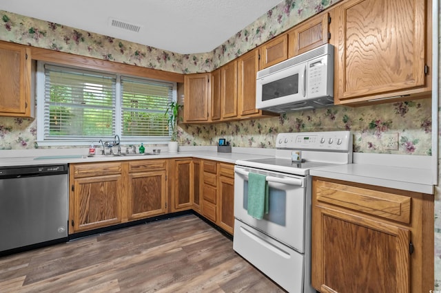311 Ashwood Ln, Myrtle Beach, SC 29588 - kitchen featuring white appliances, wallpapered walls, light countertops, light wood-style flooring, and brown cabinetry