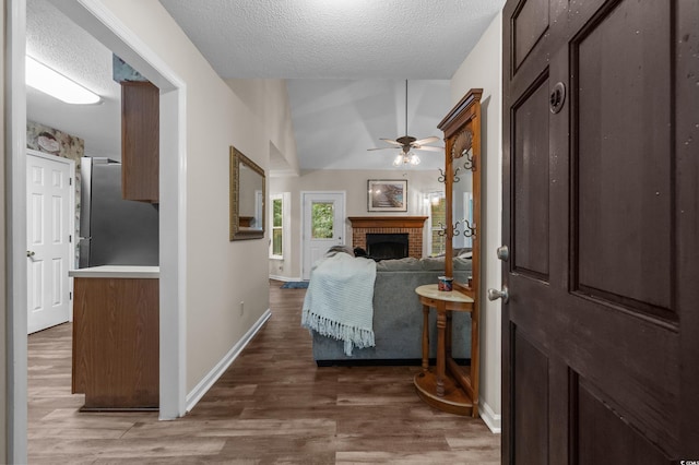311 Ashwood Ln, Myrtle Beach, SC 29588 - entrance foyer with a fireplace, a textured ceiling, wood finished floors, ceiling fan, and vaulted ceiling
