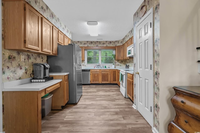311 Ashwood Ln, Myrtle Beach, SC 29588 - kitchen featuring appliances with stainless steel finishes, wallpapered walls, light wood-type flooring, light countertops, and brown cabinets