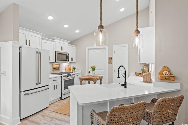 589 Boundaryline Dr NW, Calabash, NC 28467 - kitchen with appliances with stainless steel finishes, lofted ceiling, a peninsula, light wood-style floors, and white cabinetry