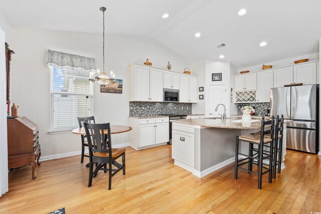 138 Copper Leaf Dr, Myrtle Beach, SC 29588 - kitchen featuring appliances with stainless steel finishes, lofted ceiling, a kitchen breakfast bar, decorative backsplash, and white cabinetry