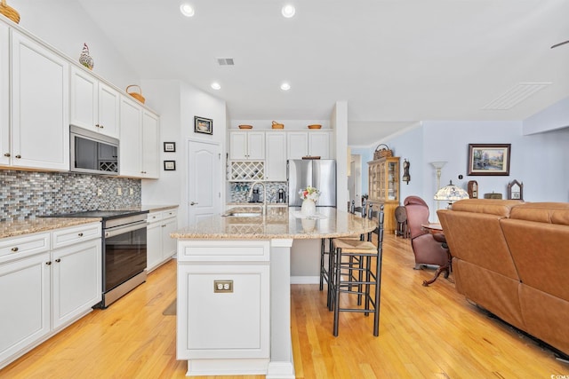 138 Copper Leaf Dr, Myrtle Beach, SC 29588 - kitchen featuring stainless steel appliances, open floor plan, decorative backsplash, a kitchen breakfast bar, and white cabinets