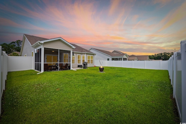 138 Copper Leaf Dr, Myrtle Beach, SC 29588 - back of property at dusk with a sunroom, a fenced backyard, and an outdoor fire pit