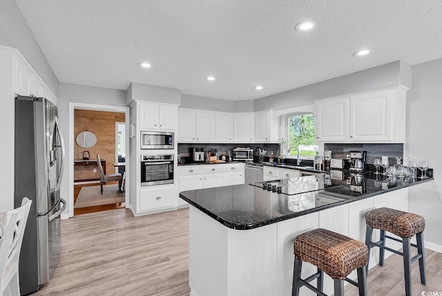 1064 Links Rd, Surfside Beach, SC 29575 - kitchen featuring appliances with stainless steel finishes, a peninsula, light wood-style floors, white cabinetry, and a textured ceiling