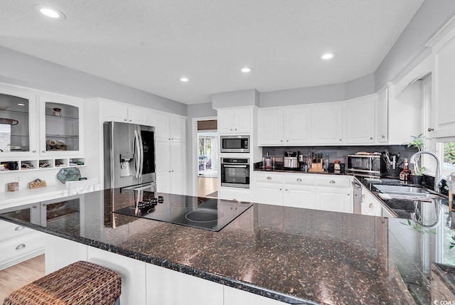 1064 Links Rd, Surfside Beach, SC 29575 - kitchen with appliances with stainless steel finishes, white cabinets, recessed lighting, decorative backsplash, and dark stone counters
