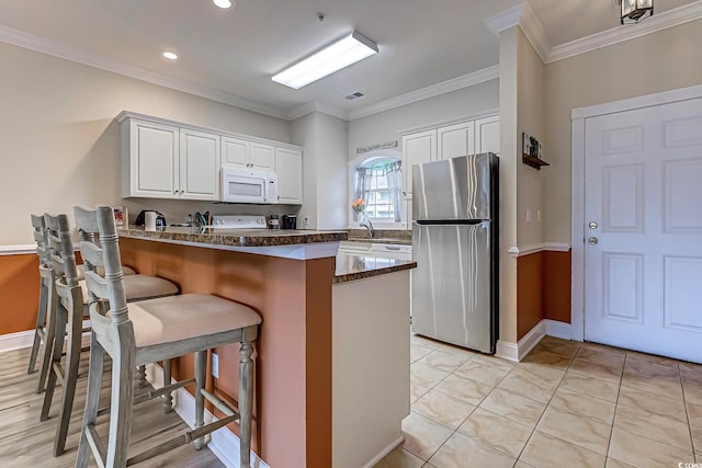 110 S Shore Blvd Unit 203, Longs, SC 29568 - kitchen featuring freestanding refrigerator, white microwave, white cabinets, a peninsula, and a kitchen breakfast bar