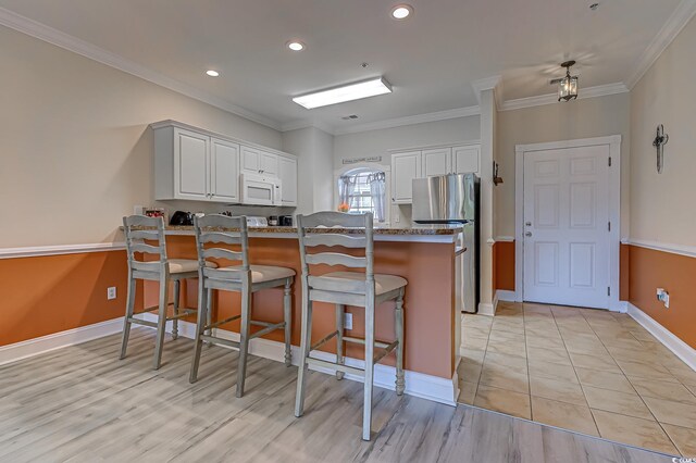 110 S Shore Blvd Unit 203, Longs, SC 29568 - kitchen featuring white microwave, freestanding refrigerator, a peninsula, ornamental molding, and a kitchen breakfast bar