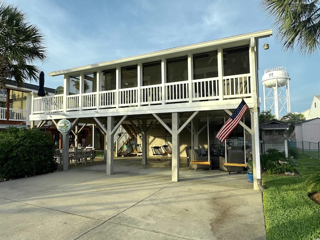 404 29th Ave N, North Myrtle Beach, SC 29582 - back of property featuring a sunroom, a carport, concrete driveway, and a patio