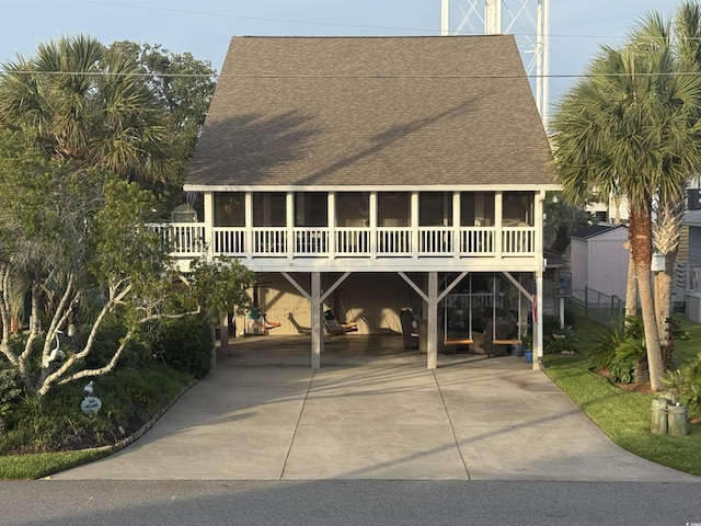 404 29th Ave N, North Myrtle Beach, SC 29582 - view of front facade with a shingled roof, a sunroom, concrete driveway, and a carport