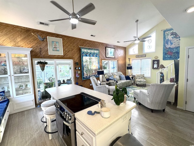 404 29th Ave N, North Myrtle Beach, SC 29582 - kitchen with stainless steel electric stove, a ceiling fan, wooden walls, white cabinetry, and light wood-style floors
