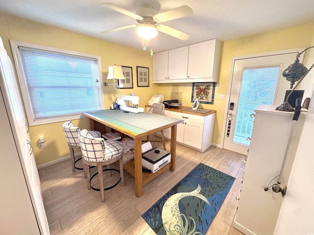 404 29th Ave N, North Myrtle Beach, SC 29582 - kitchen with light wood-style flooring, a desk, white cabinetry, and ceiling fan