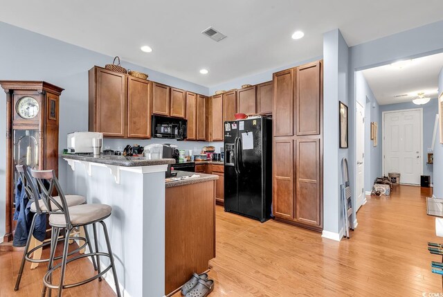 1857 Culbertson Ave Unit 1857, Myrtle Beach, SC 29577 - kitchen with black appliances, brown cabinetry, a peninsula, a breakfast bar, and light wood finished floors