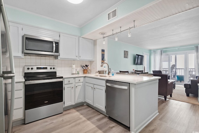 1011 S Ocean Blvd Unit 301, North Myrtle Beach, SC 29582 - kitchen featuring appliances with stainless steel finishes, open floor plan, a peninsula, light wood finished floors, and crown molding