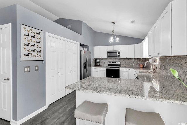3907 Stillwood Dr, Myrtle Beach, SC 29588 - kitchen with stainless steel appliances, a peninsula, lofted ceiling, dark wood-type flooring, and decorative backsplash