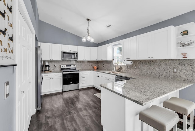 3907 Stillwood Dr, Myrtle Beach, SC 29588 - kitchen with appliances with stainless steel finishes, a peninsula, vaulted ceiling, light stone countertops, and decorative backsplash
