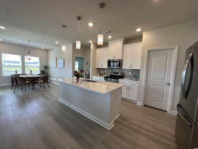 435 Rollins Dr, Longs, SC 29568 - kitchen with stainless steel appliances, wood finished floors, light countertops, tasteful backsplash, and white cabinetry