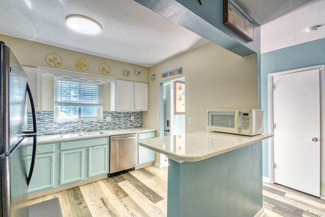 832 Villa Dr Unit 832, North Myrtle Beach, SC 29582 - kitchen featuring appliances with stainless steel finishes, a textured ceiling, light countertops, light wood-style flooring, and decorative backsplash