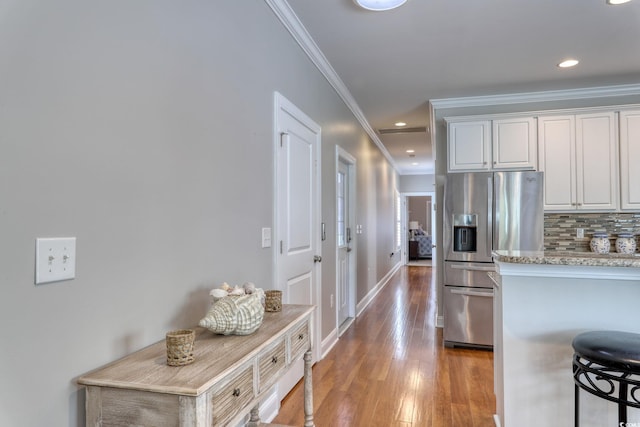 505 41st Ave S, North Myrtle Beach, SC 29582 - kitchen with stainless steel fridge, ornamental molding, light wood-style flooring, decorative backsplash, and white cabinets