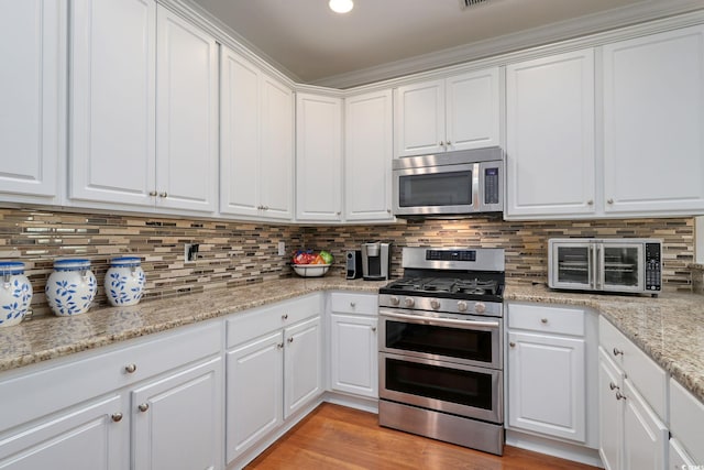 505 41st Ave S, North Myrtle Beach, SC 29582 - kitchen with appliances with stainless steel finishes, white cabinetry, tasteful backsplash, and light stone countertops