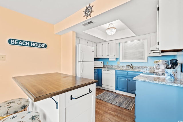212 29th Ave N Unit 204, North Myrtle Beach, SC 29582 - kitchen with white appliances, blue cabinets, a raised ceiling, wood finished floors, and a kitchen bar