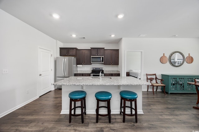 305 Forestbrook Cove Cir, Myrtle Beach, SC 29588 - kitchen with appliances with stainless steel finishes, a breakfast bar area, a kitchen island with sink, dark brown cabinets, and dark wood finished floors