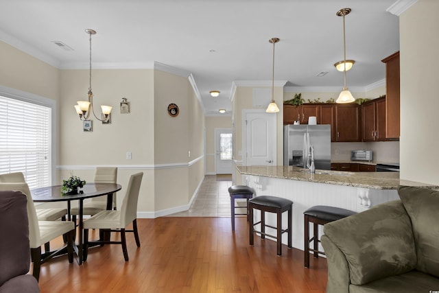 8855 Radcliff Dr NW Unit 50B, Calabash, NC 28467 - kitchen featuring stainless steel refrigerator with ice dispenser, a peninsula, a chandelier, light stone counters, and a kitchen breakfast bar