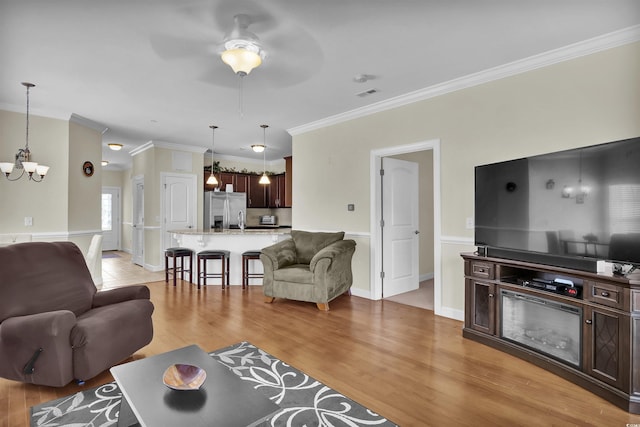 8855 Radcliff Dr NW Unit 50B, Calabash, NC 28467 - living area featuring a chandelier, a ceiling fan, light wood finished floors, and crown molding