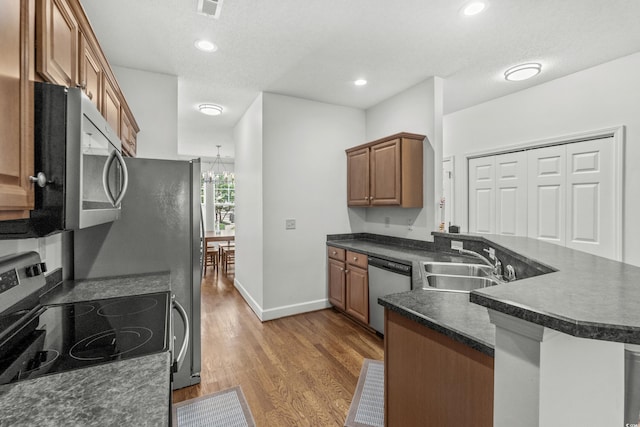 310 Lockerbie Ct Unit 1057, Myrtle Beach, SC 29577 - kitchen featuring appliances with stainless steel finishes, dark countertops, a peninsula, wood finished floors, and brown cabinets